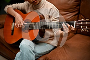 Cropped image, A gorgeous young Asian female playing guitar in her home living room