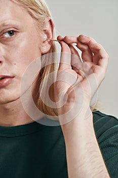 Cropped image of guy cleaning ear with ear stick