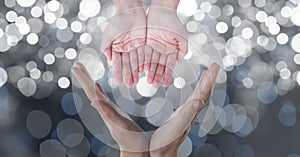 Cropped image of hands against glowing bokeh