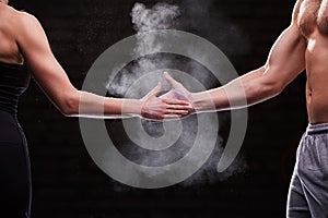 Cropped image of hands of athlete muscular man and woman against dark background. photo