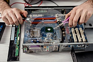 cropped image of hands with tongs fixing motherboard