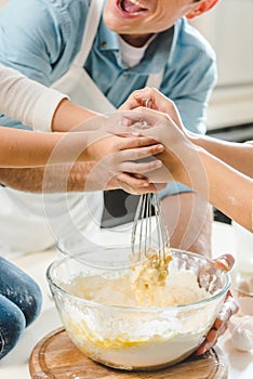 cropped image of happy family hands mixing dough in bowl together