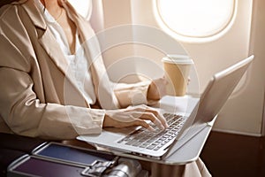 A cropped image of a hard-working businesswoman is working on her laptop during the flight