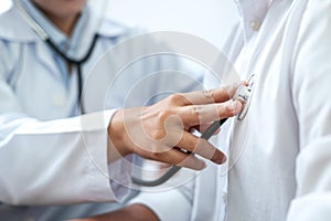 Cropped image of male doctor`s hand using stethoscope to examining heartbeat and symptom of patient while talking