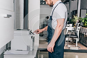 Cropped image of male handyman repairing copy machine photo