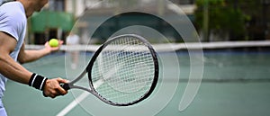 Cropped image of male tennis player with racket serving ball during match. Banner, copy space