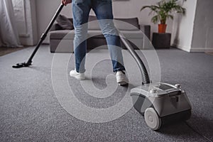 cropped image of man cleaning carpet with vacuum cleaner