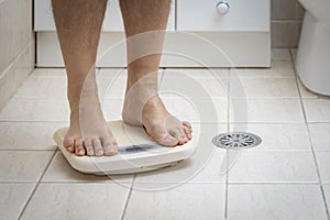 Cropped image of man feet standing on weigh scale