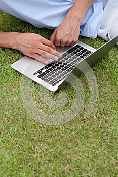 Cropped image of man using laptop on grass in park