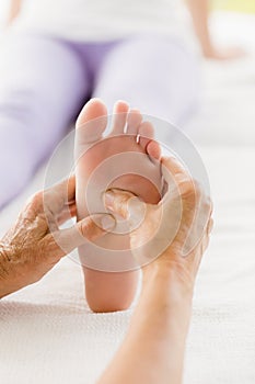 Cropped image of masseur giving foot massage to woman