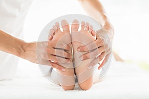 Cropped image of masseur giving foot massage to woman