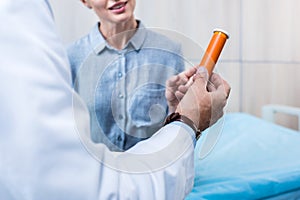 cropped image of mature male doctor giving pills to female patient
