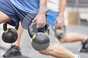 Cropped image of men lifting kettlebells at crossfit gym photo