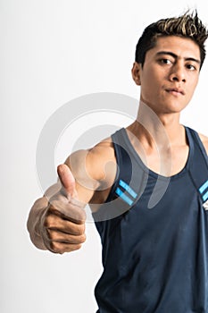 Cropped image of muscular young man wearing gym shirt stand facing to the side with thumbs up to the camera