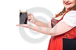 cropped image of oktoberfest waitress in traditional bavarian dress holding mug of dark beer
