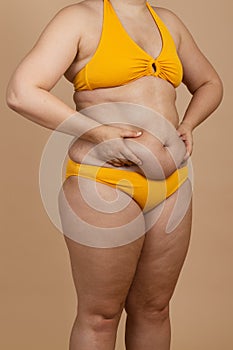 Cropped image of overweight fat woman with obesity, adipose, excess fat, yellow swimsuit. Self acceptance, body positive