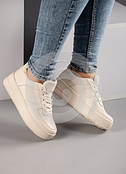 Cropped image of pair of sports shoes on female model on gray background.