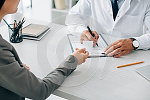 cropped image of patient giving id card to doctor to fill insurance claim form