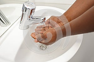 cropped image person washing hands at sink in bathroom