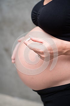 Cropped image of pregnant woman in black leggins and bra holding medicine