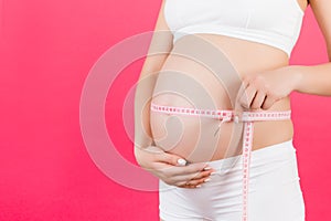 Cropped image of pregnant woman in white underwear measuring her abdomen to check baby development. Centimeter tape measure at