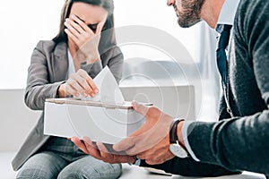 cropped image of psychologist giving napkins to crying patient