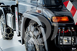 Cropped image. Right side of the car. Jeep with snow chains parked indoors at the white tile on vehicle show