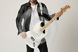 Cropped image of rock musician plays guitar and posing over white background.
