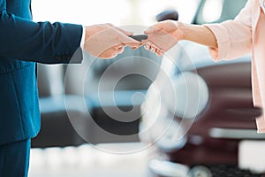 Cropped image of sales manager giving car key to customer