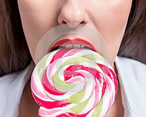 Cropped image of seductive girl biting colorful lollipop. Valentines day concept