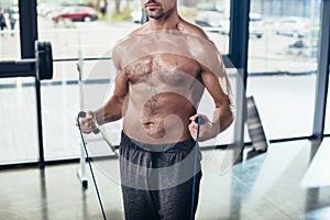 cropped image of shirtless sportsman training with jumping rope