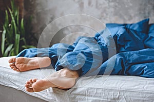cropped image of sleeping mens legs under blanket in bed