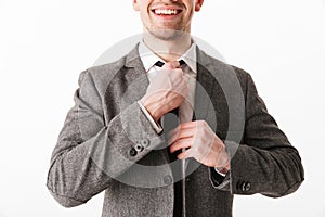 Cropped image of smiling business man in jacket corrects tie