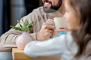 cropped image of smiling father holding cup of coffee