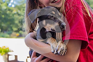 Cropped image of a smiling girl in a red teeshirt holding her puppy photo