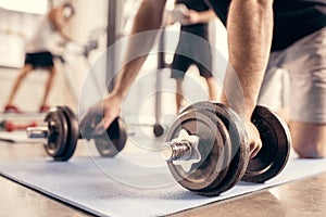 cropped image of sportsman preparing doing push ups on dumbbells