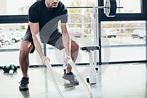 cropped image of sportsman working out with ropes photo