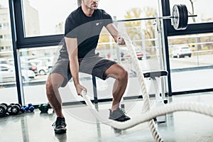 cropped image of sportsman working out with ropes photo