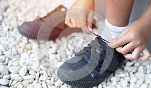 Cropped image of student boy shoes in uniform getting ready for school by tying his shoelaces