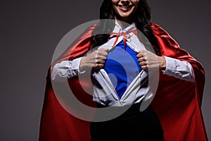 cropped image of super businesswoman in red cape showing blue shirt