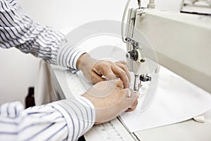 cropped image of tailor sewing cloth on sewing machine