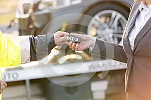 Cropped image of tow truck driver giving car key to businesswoman