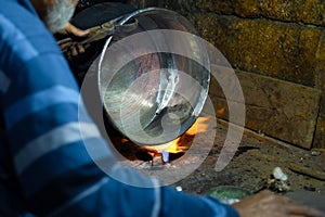 Cropped image of the traditional Turkish tinsmith covering the copper object with tin over fire