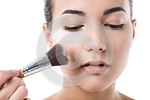 cropped image of visagiste doing makeup for young woman with face powder