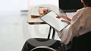 Cropped image waist up of secretary woman holding a stylus pen while sitting and using a white blank screen computer tablet .