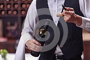 Cropped image waiter opening wine bottle