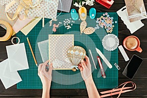 cropped image of woman adding wooden balloon to scrapbooking