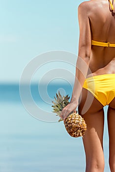 cropped image of woman in bikini holding pineapple