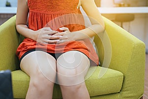 Cropped image of woman having painful stomachache at home,Female suffering from abdominal pain,Period cramps,Hands squeezing belly