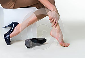 Cropped image of woman in high heels massaging her tired legs